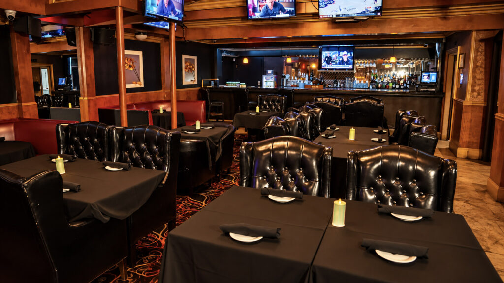 The steakhouse dining room with tufted leather chairs, candlelit tables and the bar at Rachel's North in Casselberry, Florida