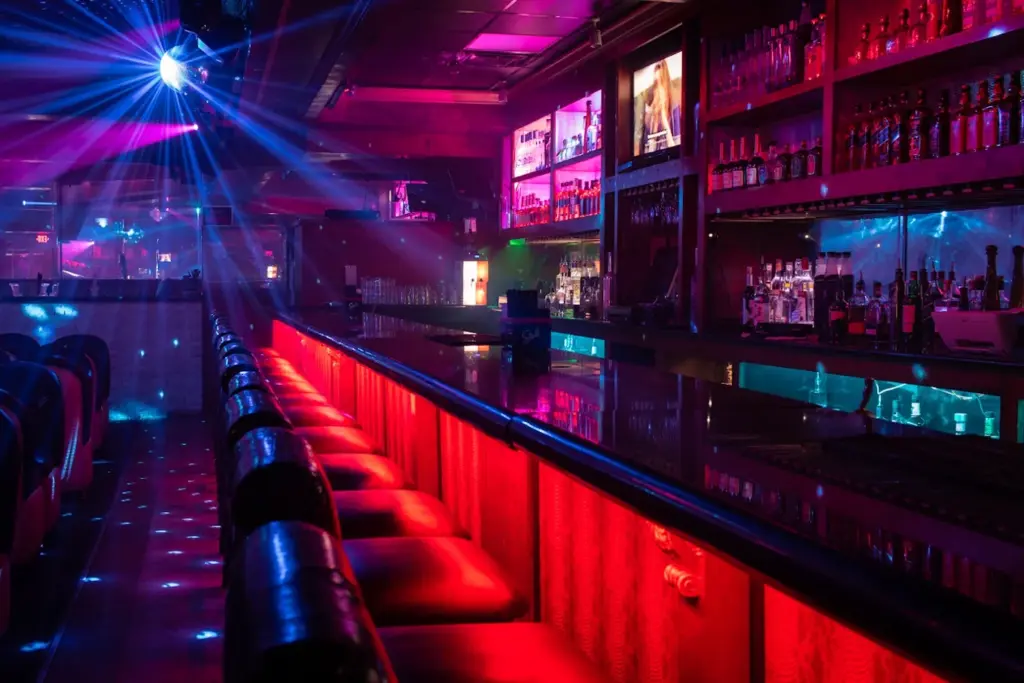 The main floor bar with red lit bar front and leather stools at Rachel's North in Casselberry, Florida