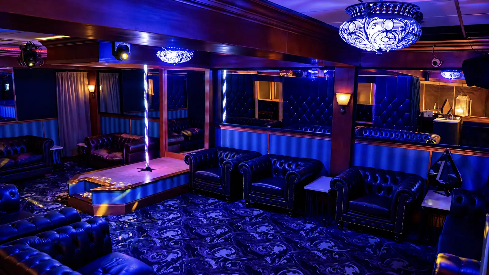 The upstairs private dance area at Rachel's North in Casselberry, Florida, with tufted leather couches, a private dance stage and a crystal chandelier