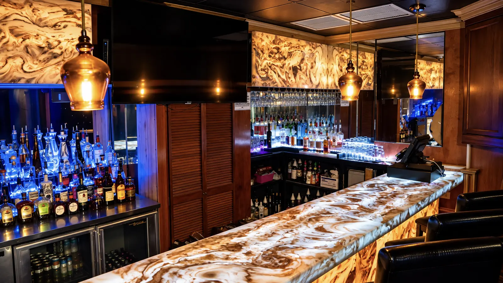 The private upstairs VIP bar at Rachel's North in Casselberry, with a backlit onyx bar top, amber pendant lights and a lit backbar