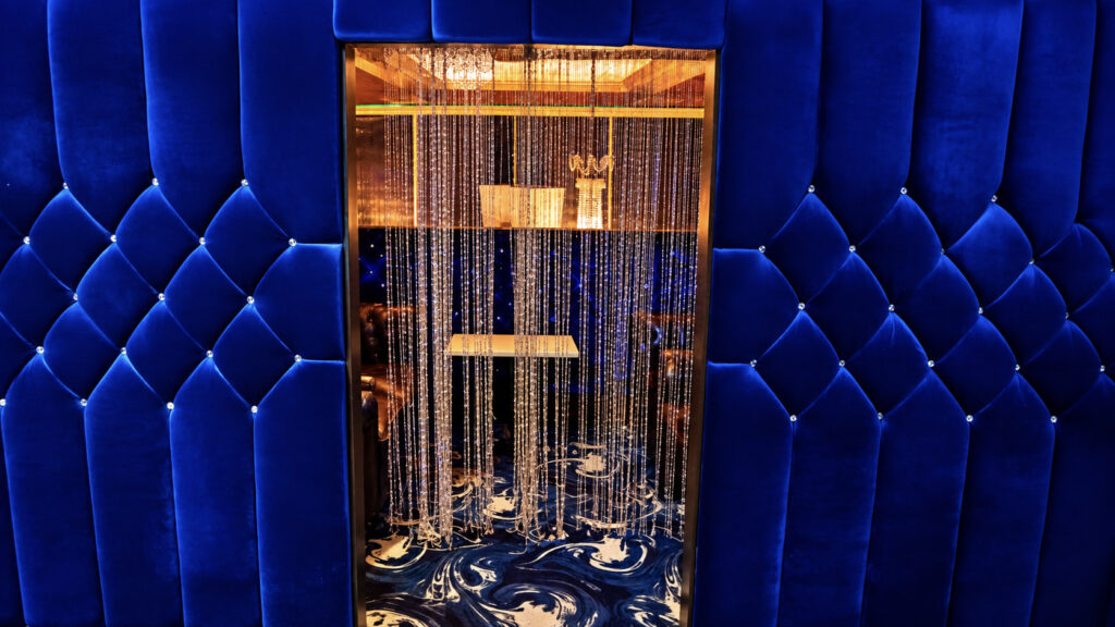 A VIP room with blue tufted velvet walls and a crystal bead curtain at Rachel's North in Casselberry, Florida